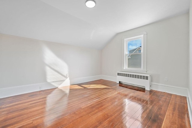 bonus room with hardwood / wood-style flooring, lofted ceiling, and radiator