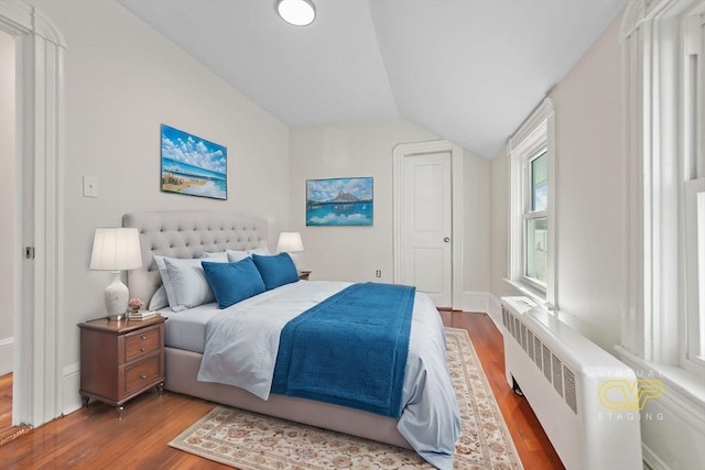 bedroom featuring radiator, wood-type flooring, and vaulted ceiling