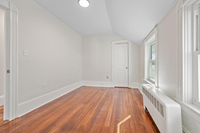 additional living space featuring radiator, wood-type flooring, and vaulted ceiling