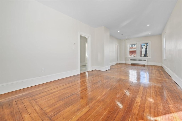 unfurnished living room with radiator and hardwood / wood-style flooring