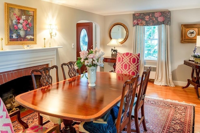 9 Mohawk Rd, Marblehead, MA 01945 - dining space featuring a fireplace, crown molding, arched walkways, wood finished floors, and radiator heating unit