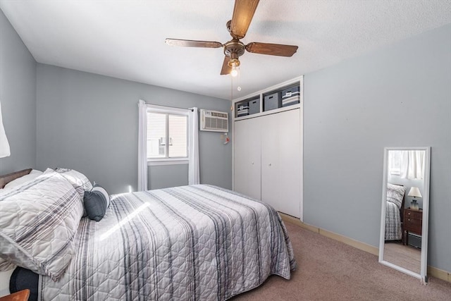 carpeted bedroom with an AC wall unit, a textured ceiling, ceiling fan, and a closet