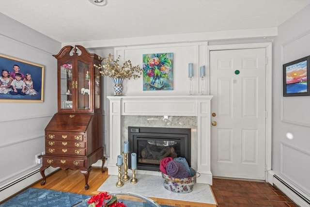 sitting room featuring a high end fireplace, dark wood-style flooring, and baseboard heating