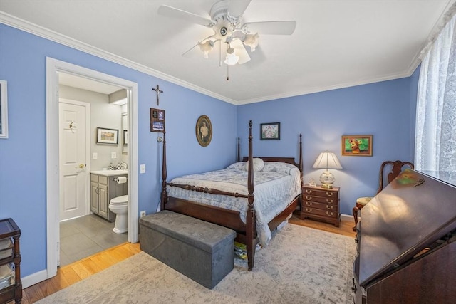 bedroom featuring a ceiling fan, crown molding, ensuite bath, and wood finished floors