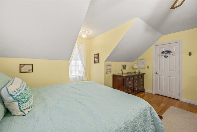 bedroom with vaulted ceiling, baseboards, and wood finished floors