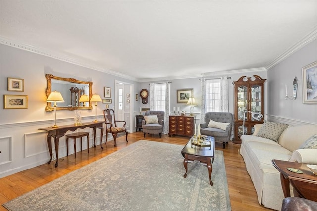 living area featuring a wainscoted wall, ornamental molding, wood finished floors, and a decorative wall