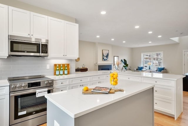 53 Driftwood Cir Unit 20, Sandown, NH 03873 - kitchen with appliances with stainless steel finishes, open floor plan, a center island, a peninsula, and recessed lighting