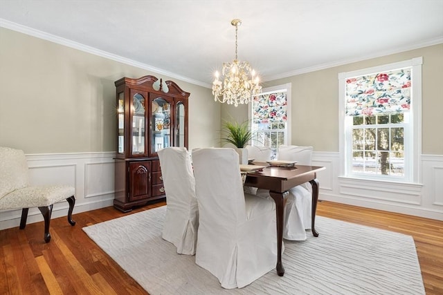 dining space with hardwood / wood-style flooring, crown molding, and a notable chandelier