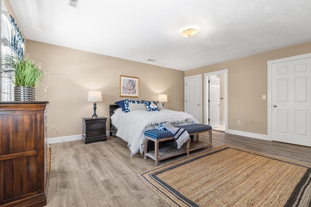 bedroom featuring ensuite bath and light hardwood / wood-style floors