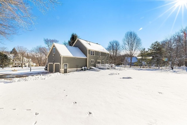 snow covered rear of property featuring a garage