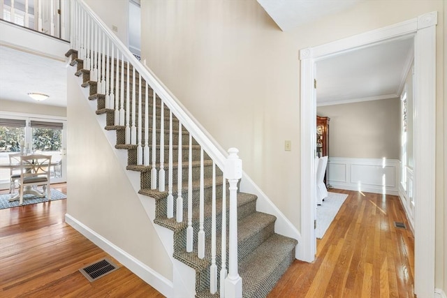 stairway with crown molding and hardwood / wood-style floors