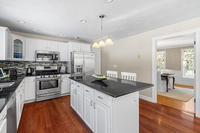 kitchen featuring dark wood-type flooring, stainless steel appliances, a center island, and white cabinets