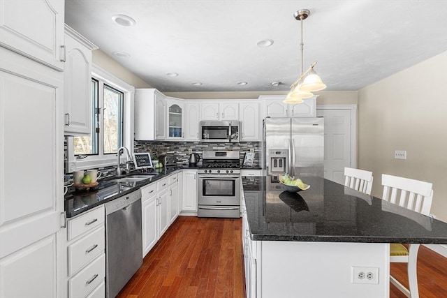 kitchen featuring sink, decorative light fixtures, appliances with stainless steel finishes, a kitchen island, and white cabinets