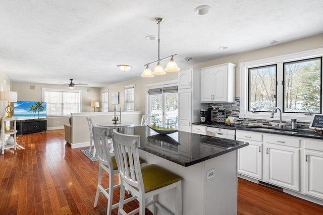 kitchen with a kitchen island, sink, pendant lighting, and white cabinets