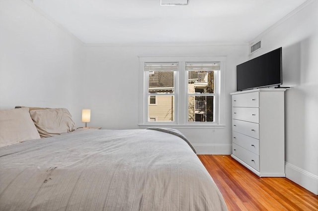 bedroom with light hardwood / wood-style floors and ornamental molding