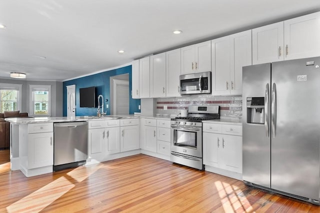 kitchen featuring sink, stainless steel appliances, kitchen peninsula, light hardwood / wood-style floors, and white cabinets