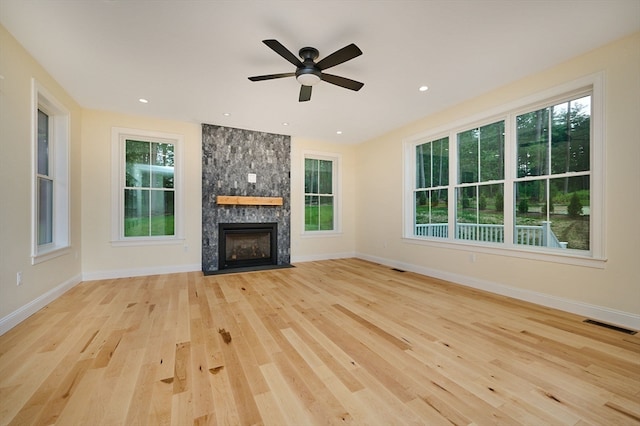 unfurnished living room featuring a large fireplace, ceiling fan, and light hardwood / wood-style floors