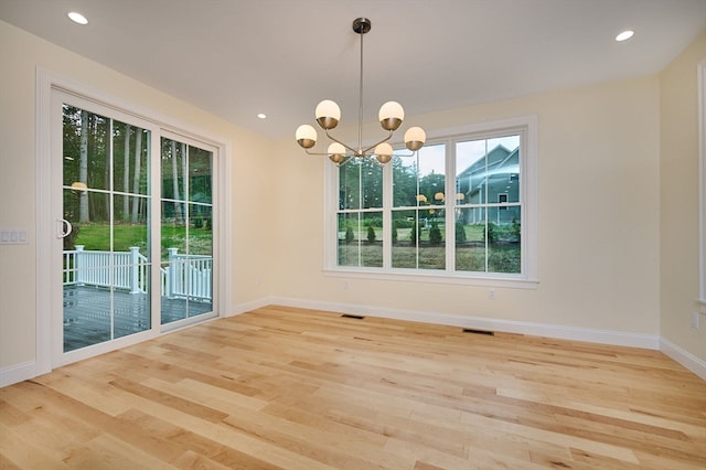 unfurnished room featuring light hardwood / wood-style flooring and an inviting chandelier