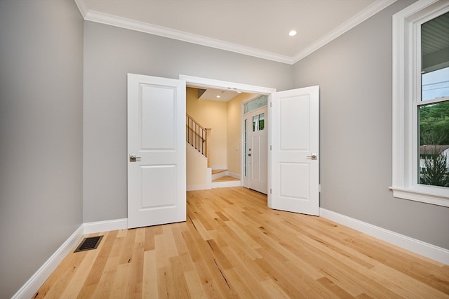 empty room with crown molding and light hardwood / wood-style floors