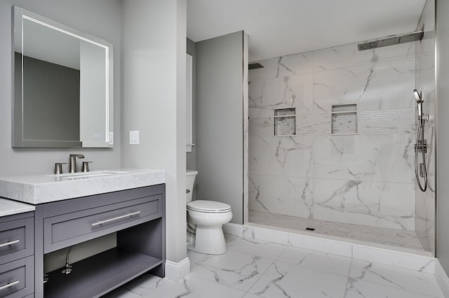 bathroom with tiled shower, vanity, and toilet