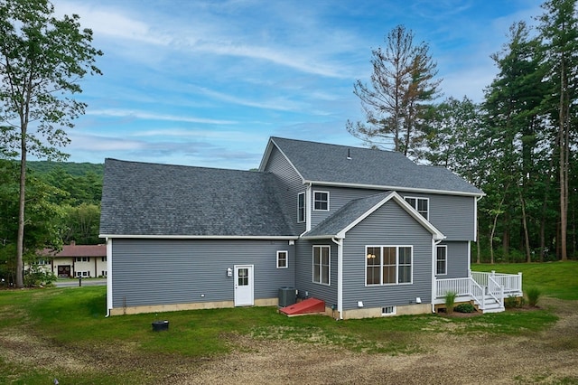 rear view of house with central AC and a yard