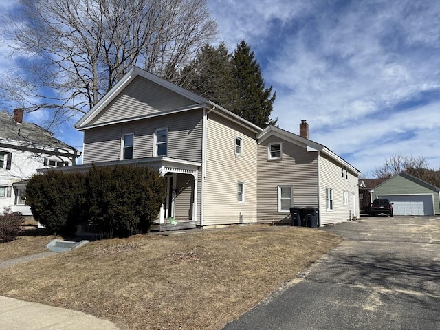 view of front facade with a garage, an outdoor structure, and a chimney