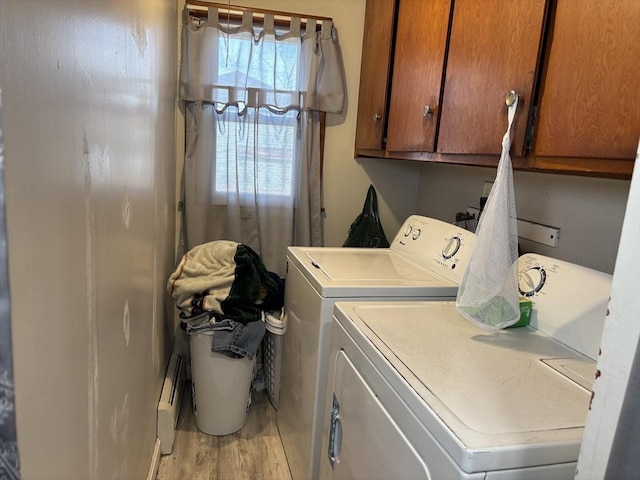 washroom featuring light wood-type flooring, cabinet space, baseboard heating, and washer and clothes dryer