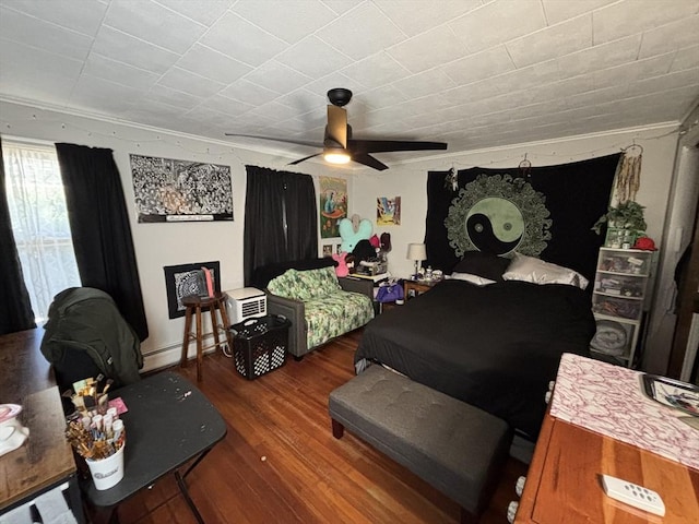 bedroom featuring a baseboard heating unit, ceiling fan, and wood finished floors