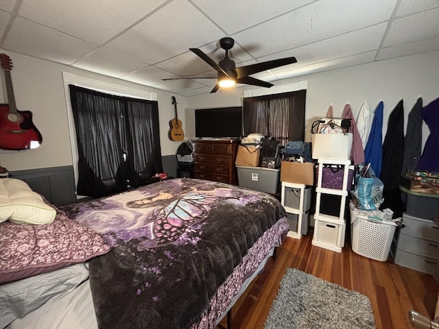 bedroom with wood finished floors, a drop ceiling, and ceiling fan