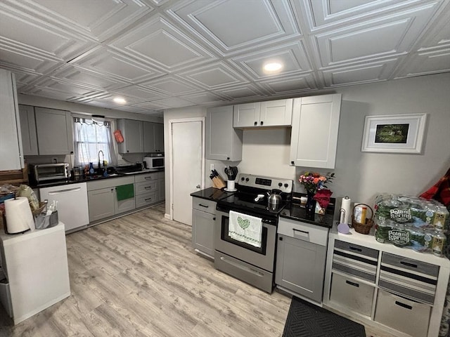 kitchen with gray cabinetry, light wood-type flooring, appliances with stainless steel finishes, an ornate ceiling, and a sink