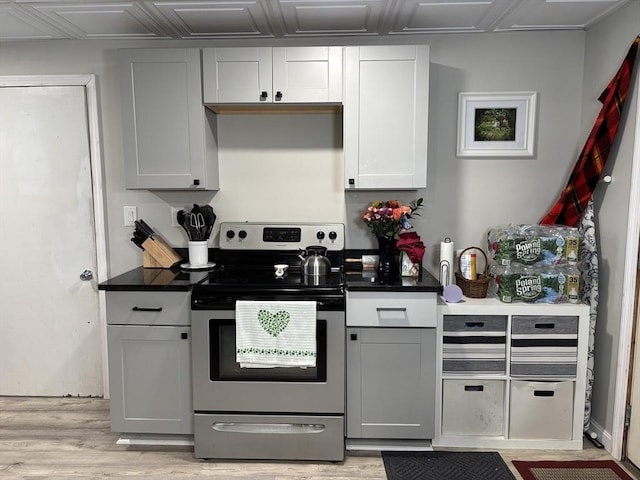 kitchen featuring stainless steel electric range oven, dark countertops, light wood-style flooring, and gray cabinets