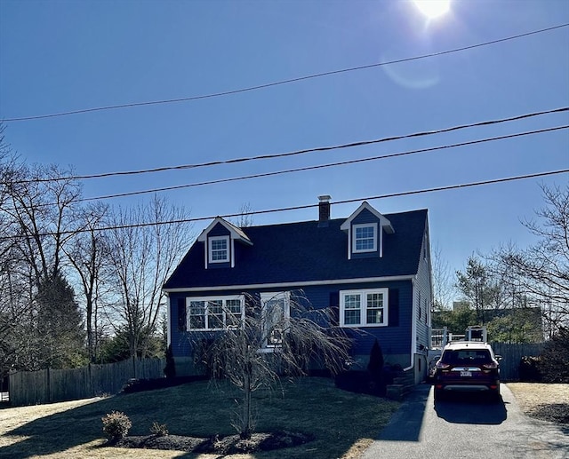 new england style home featuring a chimney and fence