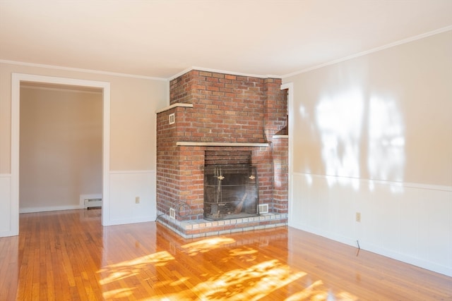 unfurnished living room featuring a brick fireplace, ornamental molding, a baseboard radiator, and hardwood / wood-style flooring