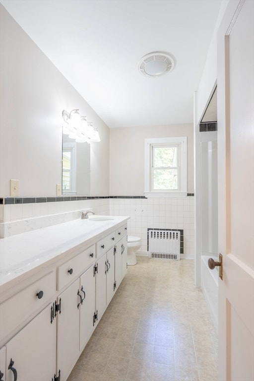 bathroom with vanity, tile walls, tile patterned flooring, radiator heating unit, and toilet