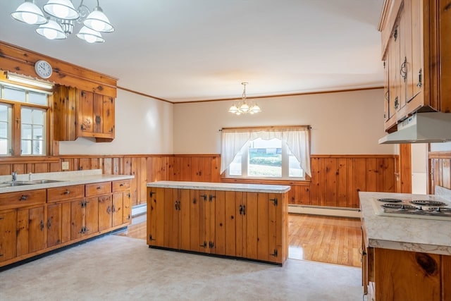 kitchen with pendant lighting, a baseboard radiator, a notable chandelier, a kitchen island, and stainless steel gas cooktop