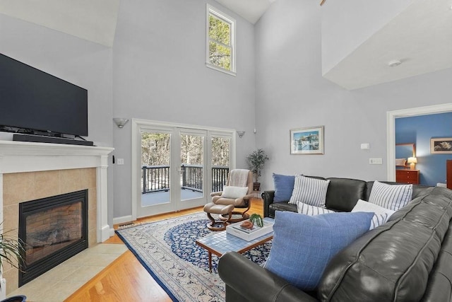 living room with a fireplace, plenty of natural light, high vaulted ceiling, and light wood-type flooring