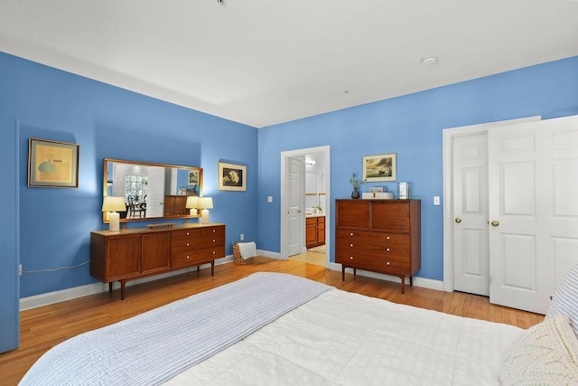 bedroom with connected bathroom and light hardwood / wood-style flooring