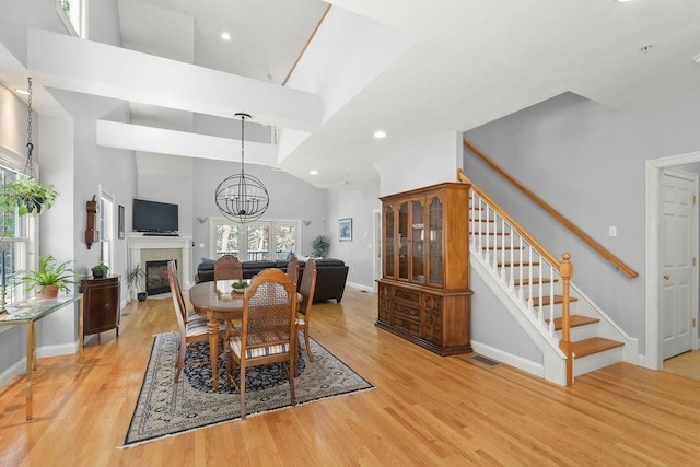 dining room featuring a towering ceiling, a chandelier, and light hardwood / wood-style floors