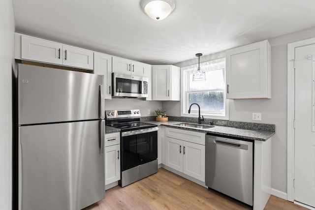 742 Daniel Shays Hwy Unit 1F, Athol, MA 01331 - kitchen with appliances with stainless steel finishes, white cabinetry, light wood finished floors, and dark stone counters