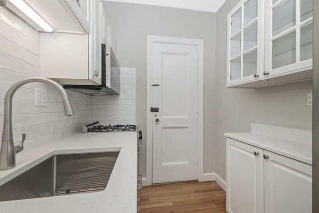 5 Arlington St Unit 31, Cambridge, MA 02140 - kitchen featuring a sink, light wood-type flooring, white cabinets, and decorative backsplash
