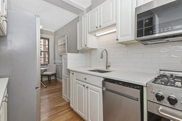 5 Arlington St Unit 31, Cambridge, MA 02140 - kitchen featuring appliances with stainless steel finishes, a sink, ornamental molding, decorative backsplash, and light countertops
