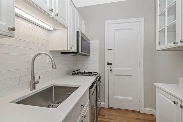5 Arlington St Unit 31, Cambridge, MA 02140 - kitchen featuring a sink, stainless steel appliances, white cabinetry, tasteful backsplash, and light wood finished floors