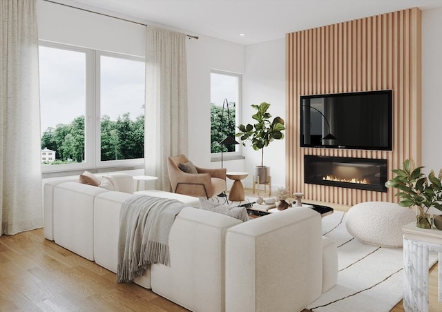 living area featuring light wood-type flooring and a glass covered fireplace