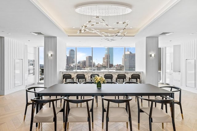 dining room with a view of city, visible vents, and a raised ceiling