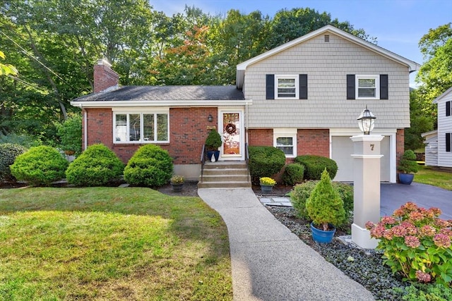 tri-level home with brick siding, a front lawn, a chimney, and an attached garage