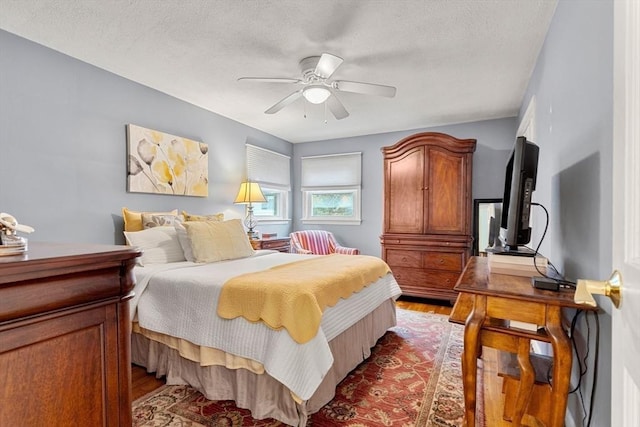 bedroom featuring light wood-type flooring, a textured ceiling, and a ceiling fan