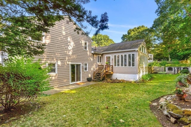 back of property with stairs, a wooden deck, a lawn, and a sunroom