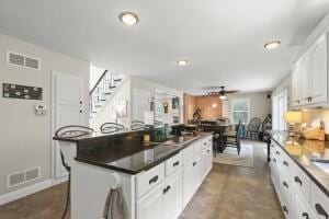 5 Lancaster Ln, Bourne, MA 02532 - kitchen featuring ceiling fan, a kitchen island, white cabinets, dark countertops, and a kitchen bar