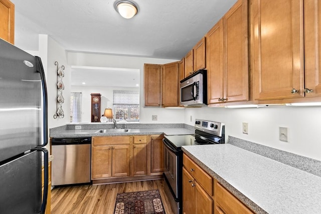 kitchen with sink, stainless steel appliances, and light hardwood / wood-style floors