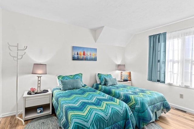 bedroom with hardwood / wood-style floors and lofted ceiling